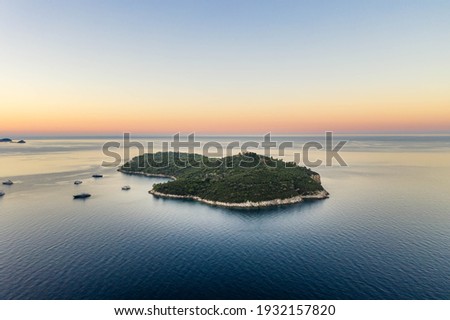 Aerial drone shot of Otok Lokrum in Adriatic sea by Dubrovnik old town port in Croatia summer before sunrise