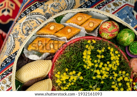 Novruz plate with Azerbaijan national pastry pakhlava and shekerbura, and colored eggs and green semeni wheat grass and nuts