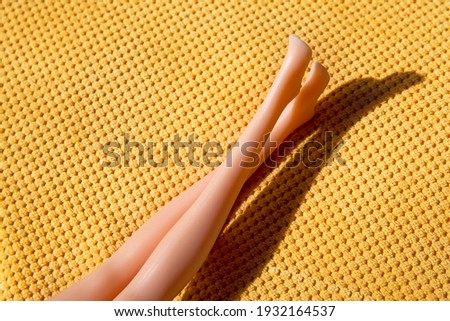 Doll legs on yellow textured background with shadow