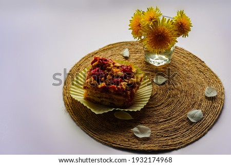 Spring breakfast, lunch - a piece of cake, a cupcake, a cake on a jute stand. A cup of flowers with yellow dandelions. On white background. 