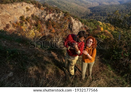 Couple spending weekend in nature. It's a beautiful sunny autumn day. Couple holding hands, walking and enjoying sun.