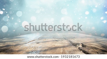 OLD WOODEN TABLE ON BLUE SNOWY BOKEH LIGHTS, NATURAL CHRISTMAS BACKDROP FOR MONTAGE OR DISPLAY WINTER PRODUCTS OR CHRISTMAS PRESENTS