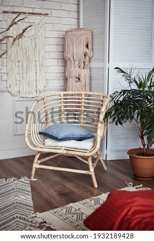 wicker chair in the interior with large flowers and a bed against a light wall