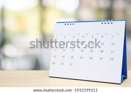 white paper desk calendar on wood table with blurred bokeh background appointment and business meeting concept