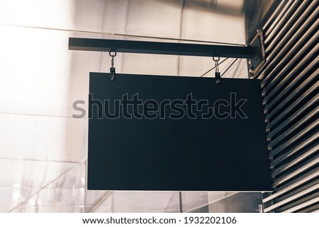 Black rectangular signboard on the wall of a modern shopping center, mockup