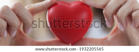 Doctor cardiologist holding red toy heart in his hands closeup. Valentines Day concept