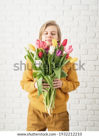 Happy beautiful woman in yellow clothes holding bouquet of tulips