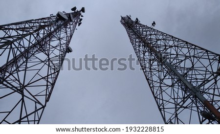 Picture two twin telecommunication towers facing the evening sky background