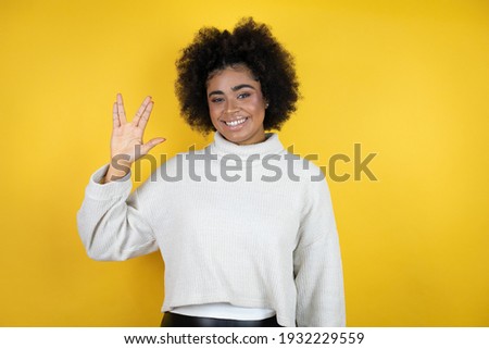 African american woman wearing casual sweater over yellow background doing hand symbol