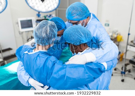 Medical professionals embracing each other in ICU. Doctors and nurses are in protective coveralls after successful treatment. They are at hospital during COVID-19.