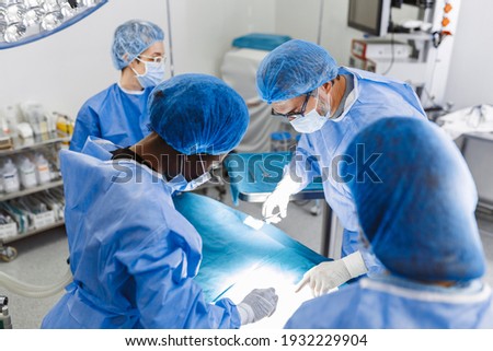 Medical team of surgeons in hospital doing minimal invasive surgical interventions. Surgery operating room with electrocautery equipment for cardiovascular emergency surgery center.