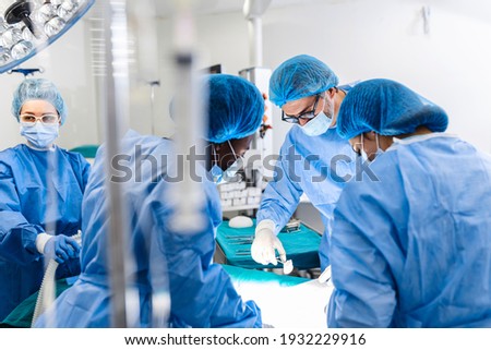 Diverse Team of Professional surgeon, Assistants and Nurses Performing Invasive Surgery on a Patient in the Hospital Operating Room. Surgeons Talk and Use Instruments. Real Modern Hospital.