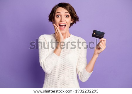 Photo portrait of shocked cheerful girl with debit plastic card touching cheek opened mouth isolated on vibrant purple color background