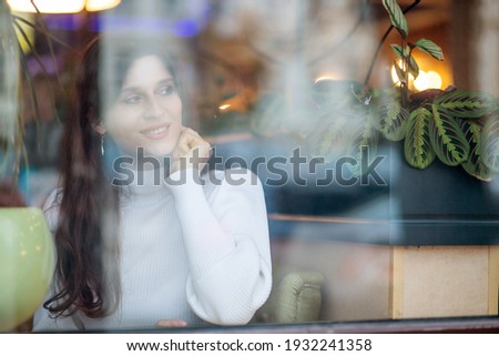 Blurred background, a woman with a phone in her hands behind a blurry glass, a special blur.
