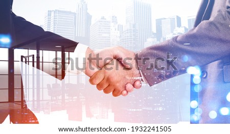 Businessmen shake hands, double exposure of office room and city buildings, night bokeh lights. Concept of international connection and teamwork