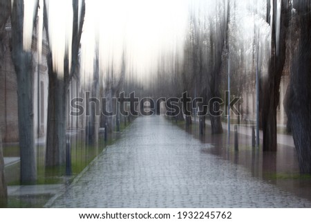 Impressionist photography with vertical camera movement at low shutter speed to achieve the effect of rain and wet ground, walk on the campus of the university of Toledo, Spain,