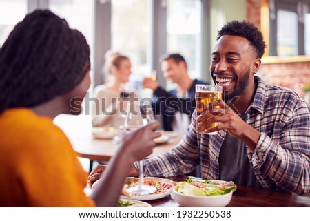 Smiling Young Couple On Date Making Toast Before Enjoying Pizza In Restaurant Together Royalty-Free Stock Photo #1932250538