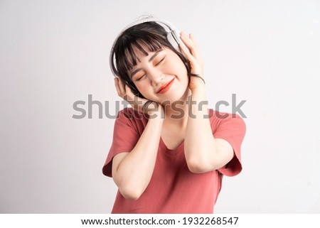 Young Asian woman wearing wireless headphones to listening music on white background