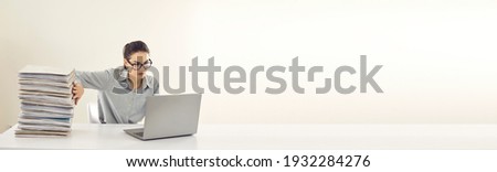 No more piles of papers, store them in digital computer database instead. Office manager or accountant sitting at desk, doing paperwork, entering data in electronic system on laptop. Copy space banner Royalty-Free Stock Photo #1932284276