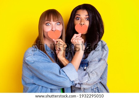 Photo of two pretty persons arm hold small red paper heart card cover each other lips isolated on yellow color background