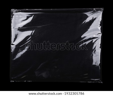 Transparent plastic wrap on the black background. Clean blank texture overlay effect template. Isolated wrinkle surface branding mock-up. Black pack packaging bag. Royalty-Free Stock Photo #1932305786
