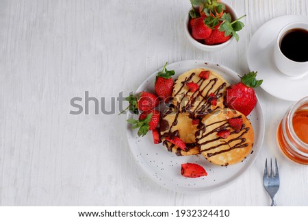 Pancake with strawberry and honey on white background