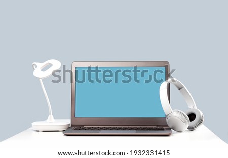 Laptop. Mockup screen and headphones on white desk and plain background banner. Distant learning. working from home, online courses or support minimal concept. Helpdesk or call center headset