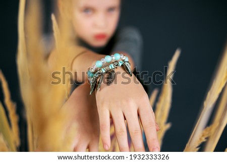 A beautiful and stylish bracelet made of blue beads and feathers on the hand of a teenage girl.