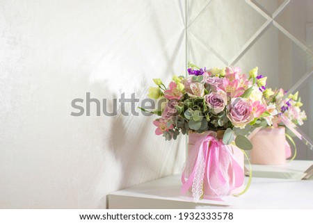 Beautiful bouquet of flowers in pink round box on a white table. Gift for holiday, birthday, Wedding, Mother's Day, Valentine's day, Women's Day. Floral arrangement in a hat box.