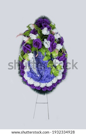 Wreath with artificial flowers for tombstone on gray background