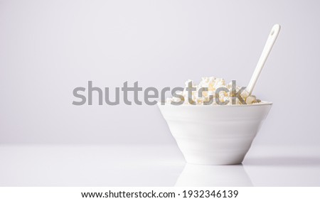 fresh Cottage Cheese In white Bowl on a light background.