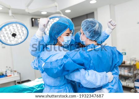 Partial view of hard-working male and female hospital team in full protective wear standing together in group embrace. Royalty-Free Stock Photo #1932347687