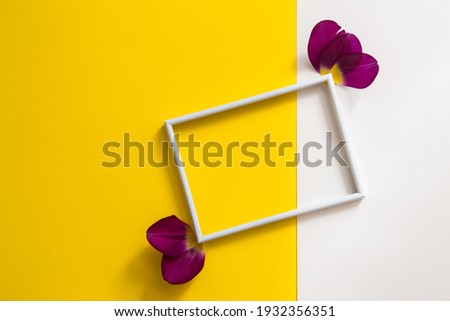 Empty photo frame with flowers on geometric paper white and yellow colorful background. Flat lay, top view. Greeting card for Birthday, Wedding, Mothers or Womens Day.