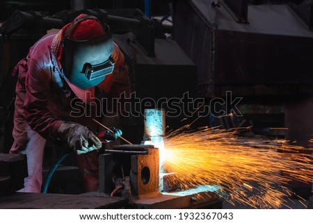 Welder use carbon air arc gouging for hot work cutting or gouging heavy metal steel structure in the fabrication factory. Royalty-Free Stock Photo #1932367043