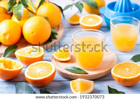 Two glasses of fresh juice, fruit squeezer and ripe fresh oranges on blue wooden table top, fresh orange juice making, top view Royalty-Free Stock Photo #1932370073