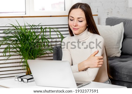 Portrait of young woman using laptop at home.