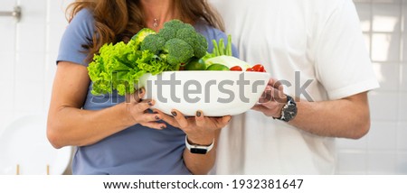 banner picture of young caucasian couple holding bowl of fruit and vegetable in hand and standing in kitchen to prepare breakfast. family together concept