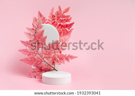White podium with branch of leaves and arch to show cosmetic products. Pink color background for branding and packaging presentation.