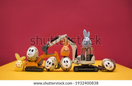 models of toy excavators, Easter bunnies, quail eggs with painted smiles and eyes. Business congratulations concept for construction companies. postcard. copy space