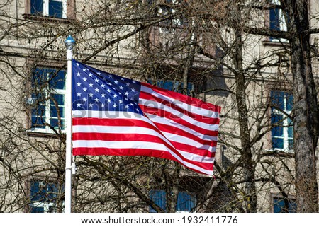 USA, United States, American flag waving in the city with buildings and park on background, 11 September 
