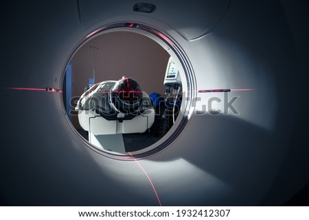 Senior man going through a Computerised Axial Tomography (CAT) Scan medical test, examination in a modern hospital (colour toned image; shallow DOF) Royalty-Free Stock Photo #1932412307