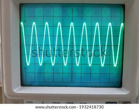 The sinusoidal waveform of electric signal displays on the oscilloscope monitor. Royalty-Free Stock Photo #1932418730
