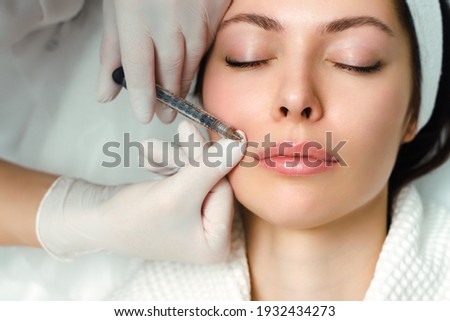 Lip augmentation and correction procedure in a cosmetology salon. The specialist makes an injection in the patient's lips Royalty-Free Stock Photo #1932434273