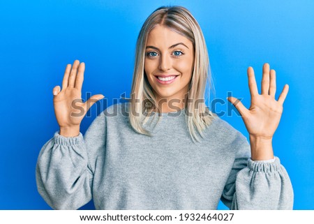 Beautiful blonde woman wearing casual clothes showing and pointing up with fingers number nine while smiling confident and happy. 