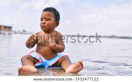 Adorable african american toddler sitting at the beach.