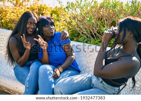 Three african american friends smiling happy taking photo using camera at the park.