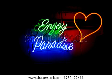 Neon lettering: enjoy paradise -background