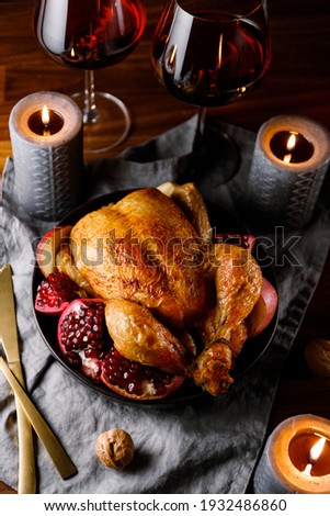 Whole roast chicken with pomegranate, apple and red wine on a festive table. 