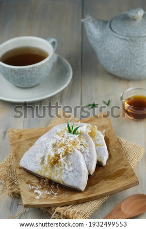 Boiled talas Bogor or Bogor taro served with shredded coconut topping and palm sugar on wooden plate and wooden table.
