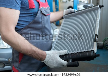 Spare parts. Radiator of the engine cooling system close-up. A car mechanic checks the new radiator before replacing the faulty one. Repair and maintenance. Royalty-Free Stock Photo #1932499601